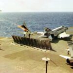 An A-4C Skyhawk of Attack Squadron 66 (VA-66), known as the “Waldos”, approaches the USS Enterprise (CVN-65), accompanied by the USS Bainbridge (DLGN-25) and the USS Long Beach (CGN-9).